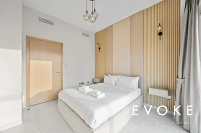 a bedroom with a large white bed with towels on it at Full Burj & Fountain View - Evoke 2BR at Burj Royale in Dubai