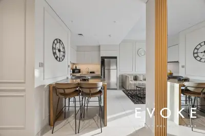 a kitchen with bar stools and a clock on the wall at Full Burj & Fountain View - Evoke 2BR at Burj Royale in Dubai