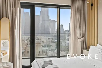 a bedroom with a large window with a view of the city at Full Burj & Fountain View - Evoke 2BR at Burj Royale in Dubai