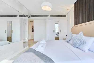 a bedroom with a large white bed and a mirror at 1BR Sky Gardens Balcony with Stunning DIFC View in Dubai