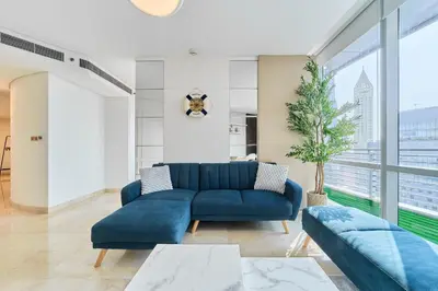 a living room with a blue couch and a large window at 1BR Sky Gardens Balcony with Stunning DIFC View in Dubai