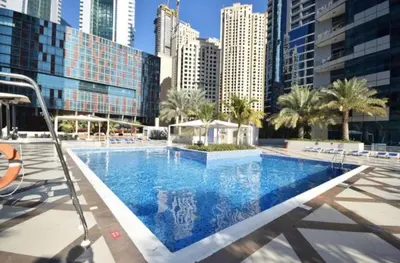a large swimming pool in a city with tall buildings at JBR Studio Apartment - Bay Central in Dubai