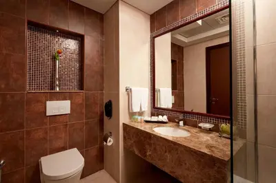 a bathroom with a sink and a toilet and a mirror at Treppan Hotel & Suites By Fakhruddin in Dubai