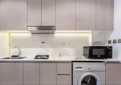 a white kitchen with a sink and a microwave at Cosy studio in Dubai