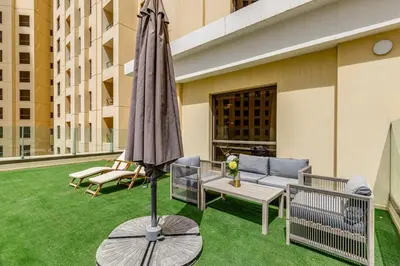 a patio with an umbrella and a couch and a table at Shams, JBR - 2BR Apartment - Allsopp & Allsopp in Dubai
