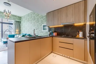 a kitchen with brown cabinets and a living room at Oxford Boulevard - 1 BR Apartment - Allsopp & Allsopp in Dubai