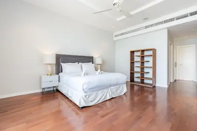 a white bedroom with a large white bed and wooden floors at Stunning Sea View 3BR with Private Beach in Dubai
