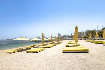 a row of yellow lounge chairs and umbrellas on a beach at Stunning Sea View 3BR with Private Beach in Dubai