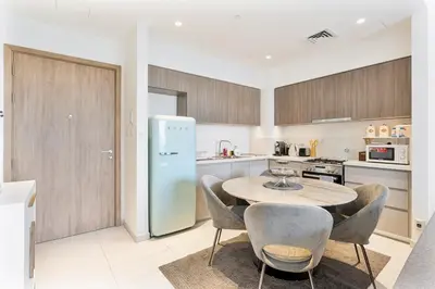 a kitchen with a table and chairs and a refrigerator at Bright 1BR APT in Dubai Hills Near Burj Khalifa in Dubai