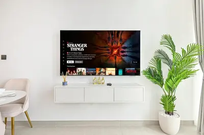 a white living room with a tv on a wall at Golden Stays - Binghatti Tulip I Chic 1BR Apartment I Balcony Views I JVC Dubai in Dubai