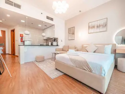 a bedroom with a large bed and a kitchen at Cozy Studio Themed Designed In JVT in Dubai