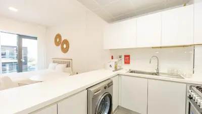 a kitchen with white cabinets and a dishwasher at Cozy Studio in JVC in Dubai