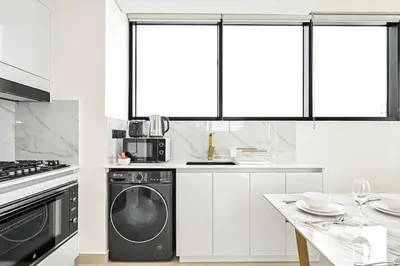 a kitchen with a washer and dryer and a table at Golden Stays - Private Pool in Binghatti Tulip I Prime JVC 2BR I Balcony Access in Dubai