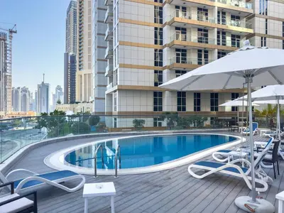 a swimming pool with chairs and umbrellas and a building at Elegant 1BR near from Dubai Mall & Burj Khalifa in Dubai