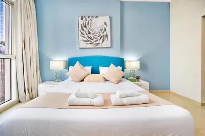 a bedroom with a large white bed with blue walls at Elegant 1BR near from Dubai Mall & Burj Khalifa in Dubai