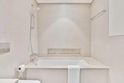 a white bathroom with a tub and a toilet at Citihome Luxury Finishing 1BR City View in Dubai