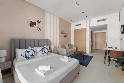 a bedroom with a bed and a living room at VayK - Contemporary and Cozy Studio in JVC in Dubai