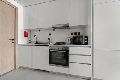 a kitchen with white cabinets and a stove at VayK - Contemporary and Cozy Studio in JVC in Dubai