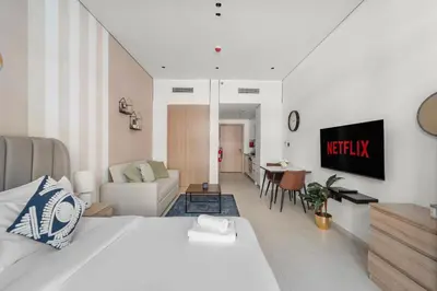 a bedroom with a bed and a living room at VayK - Contemporary and Cozy Studio in JVC in Dubai