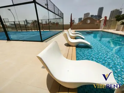 a swimming pool with white chairs in a building at Luxury 1BHK Pool Paddle Sauna in Dubai