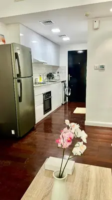 a kitchen with a refrigerator and a vase with flowers in it at Zing Holiday Home in Dubai