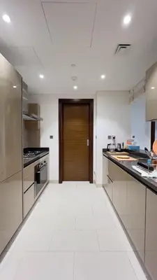 a kitchen with white floors and a wooden door at Sobha Hartland Greens 2BR near Dubai Mall in Dubai