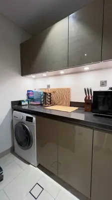 a kitchen with a washing machine and a microwave at Sobha Hartland Greens 2BR near Dubai Mall in Dubai