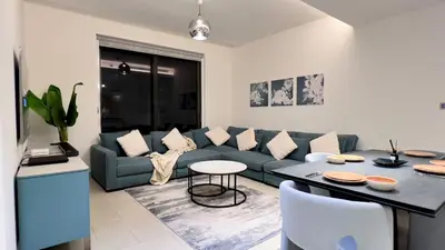 a living room with a blue couch and a table at Sobha Hartland Greens 2BR near Dubai Mall in Dubai