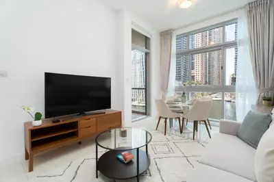a living room with a television and a table with chairs at Gala Guests - Iris Blue Luxe Living Collection in Dubai