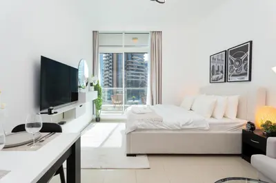 a white living room with a bed and a tv at Tranquil Studio at Botanica in Dubai