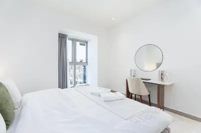 a white bedroom with a bed and a desk at Gala Guests - Princess Tower Suites Dubai Marina in Dubai