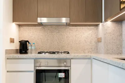 a kitchen with white cabinets and a stove top oven at KeyRock - Palm View Apt with Pool & Gym Access in Dubai