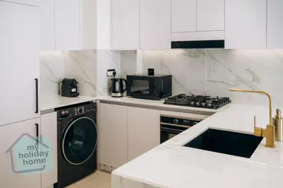 a kitchen with a washing machine and a microwave at Brand New 1BR Fully Furnished in Dubai