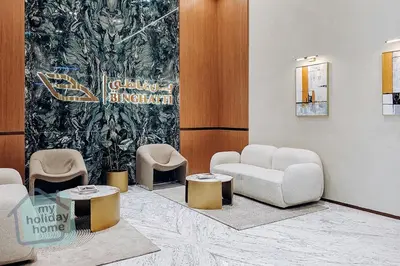 a lobby with chairs and tables and a wall at Brand New 1BR Fully Furnished in Dubai