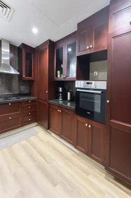 a kitchen with wooden cabinets and a stove at 5 Star Burj Khalifa View Spacious 2BR Next to Dubai Mall in Dubai