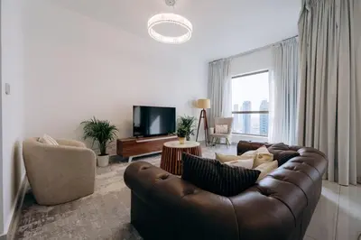 a living room with a brown leather couch and a tv at Top Holiday Location - Canal View - Beach Access in Dubai