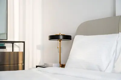 a bed with a gold lamp next to a white pillow at SettlerHomes - Lux 20F Stay With Gym, Pool & Cinema in Dubai