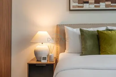 a bedroom with a bed with a lamp on a night stand at City View with Balcony Next to Dubai Water Canal, Walking Distance to Marine Transport Station, Easy Downtown Access, Reva Residences, Business Bay by Deluxe Holiday Homes in Dubai