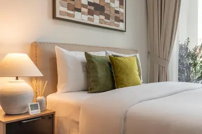 a bedroom with a bed with white sheets and green pillows at City View with Balcony Next to Dubai Water Canal, Walking Distance to Marine Transport Station, Easy Downtown Access, Reva Residences, Business Bay by Deluxe Holiday Homes in Dubai