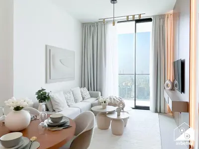 a white living room with a white couch and a table at Luxury 1BR l Balcony, Pool, Gym & Prime Location in Dubai