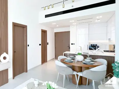 a kitchen and dining room with a wooden table and white chairs at Luxury 1BR l Balcony, Pool, Gym & Prime Location in Dubai