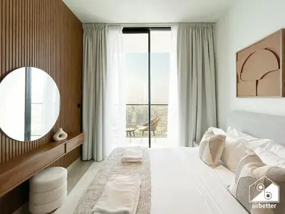 a bedroom with a large bed with a mirror and a window at Luxury 1BR l Balcony, Pool, Gym & Prime Location in Dubai