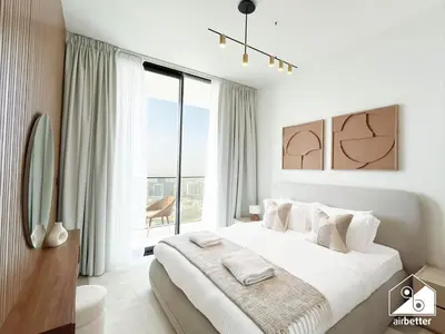 a white bedroom with a large bed and a large window at Modern 1BR in JVC l Pool, Gym, Parking in Dubai