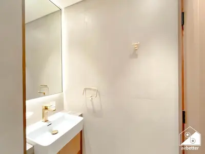 a white bathroom with a sink and a mirror at Modern 1BR in JVC l Pool, Gym, Parking in Dubai