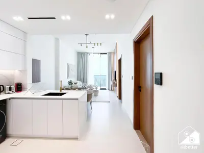 a kitchen with white cabinets and a living room at Modern 1BR in JVC l Pool, Gym, Parking in Dubai