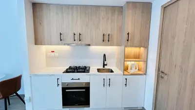 a kitchen with white cabinets and a sink at studio in best community-podium level with terrace in Dubai