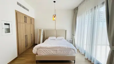 a bedroom with a bed and a large window at studio in best community-podium level with terrace in Dubai