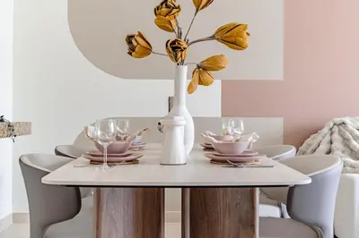 a dining room table with a white vase with flowers at The Smart Concierge - Burj Views in Dubai