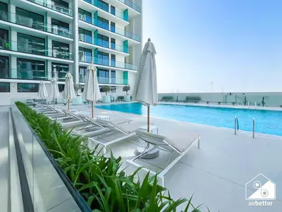 a row of lounge chairs with umbrellas next to a swimming pool at Refreshing Retreat with Pool Access and Balcony in Dubai