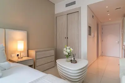 a bedroom with a bed and a table with flowers on it at Seven Palm Jumeirah Studio - Private Beach Access in Dubai